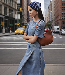 A woman in a denim outfit and bandana stands on a city street with a yellow taxi and buildings in the background. carousel Product Image 1