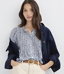 A woman in a floral blouse and a navy jacket stands against a plain white background. carousel Product Image 2