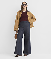 A woman in a brown jacket and wide-leg jeans stands against a plain white background, holding a small brown purse. carousel Product Image 1