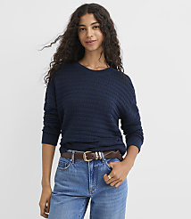 A woman in a navy blue sweater and jeans stands against a plain white background. carousel Product Image 2