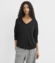 A woman in a black v-neck sweater and plaid pants stands against a plain white background. carousel Product Image 2