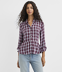 A woman in a burgundy plaid peplum shirt and light wash jeans stands against a plain white background. carousel Product Image 1