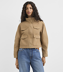 A young woman in a brown jacket and striped shirt stands against a plain white background. carousel Product Image 1
