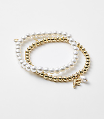 Two bracelets, one with pearls and the other with gold beads and an "F" charm, rest on a plain white background. carousel Product Image 1