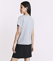 A woman in a grey t-shirt and black skirt stands against a plain white background. carousel Product Image 3