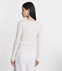 A woman in a cream-colored ribbed sweater and white pants stands against a plain white background. carousel Product Image 3