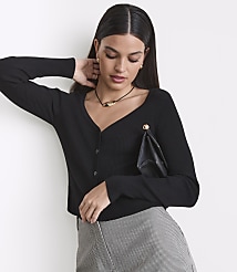 A woman in a black ribbed cardigan and patterned skirt poses against a plain white background. carousel Product Image 2