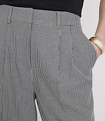 A person's hand, adorned with a gold bracelet, rests in the pocket of houndstooth patterned pants against a plain white background. carousel Product Image 4