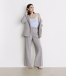A woman in a light blue tank top and a pinstripe suit stands against a plain white wall. carousel Product Image 1