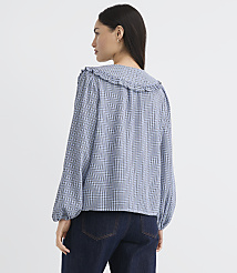 A woman in a blue and white checkered blouse with a ruffled collar stands against a plain white background. carousel Product Image 3