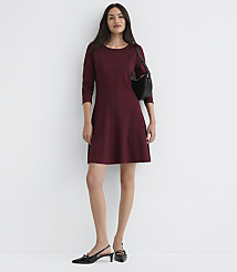 A woman in a maroon dress and black slingback heels stands against a plain white wall, with a black purse slung over her shoulder. carousel Product Image 1