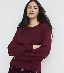A woman in a maroon sweater and patterned skirt stands with her arms crossed against a plain white background. carousel Product Image 1