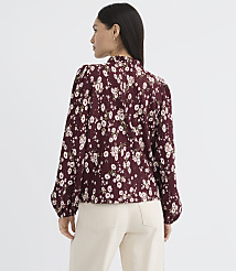 A woman in a floral blouse and light-colored pants stands against a plain white background. carousel Product Image 3