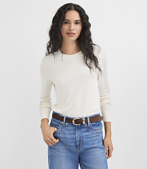 A woman in a cream sweater and blue jeans stands against a plain white background. carousel Product Image 2