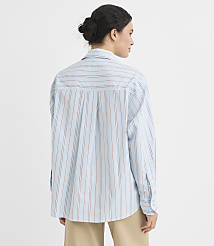 A woman in a light blue pinstripe shirt stands against a plain white background. carousel Product Image 3