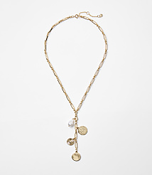 A gold necklace with a pearl and coin charms hangs against a plain white background. carousel Product Image 1