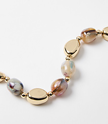 A close-up of a necklace with irregular, marbled beads and gold oval accents rests on a plain white background. carousel Product Image 2