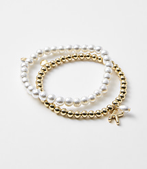 Two bracelets, one with pearls and the other with gold beads and a charm, rest on a plain white background. carousel Product Image 1
