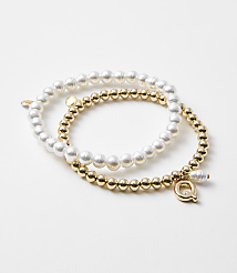 Two bracelets, one with pearls and the other with gold beads, rest on a plain white background. carousel Product Image 1