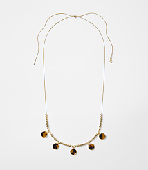 A delicate gold necklace with small beads and tortoise shell pendants hangs against a plain white background. carousel Product Image 1