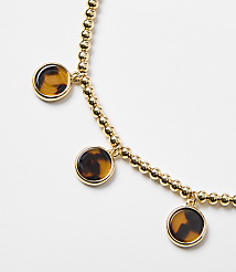 A gold beaded bracelet with three tortoise shell charms hangs against a plain white background. carousel Product Image 2