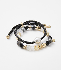 Two beaded bracelets, one with a black cord and white dots, are arranged on a plain white background. carousel Product Image 1