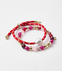 Two red beaded bracelets with gold accents and a pearl are arranged on a white background. carousel Product Image 1