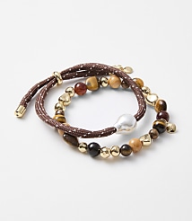 Two beaded bracelets, one with a large pearl and the other with various stones and gold accents, are arranged on a plain white background. carousel Product Image 1