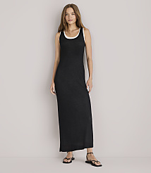 A woman in a black maxi dress and denim jacket leans against a white wall. carousel Product Image 1