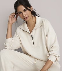 A woman in a cream-colored quarter-zip sweatshirt and matching pants poses against a plain, light gray background. carousel Product Image 2