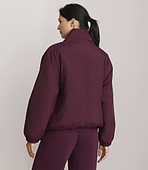 A woman in a maroon puffer jacket and matching pants stands against a plain, light purple background. carousel Product Image 3