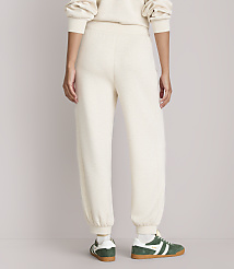 A person wearing cream-colored sweatpants and green and white sneakers stands against a plain, light-colored background. carousel Product Image 3