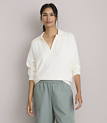 A woman in a cream-colored collared sweater and green pants stands against a plain, light gray background. carousel Product Image 2