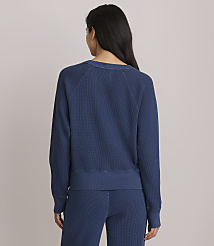 A woman in a blue waffle-knit sweatshirt and matching pants stands with her back to the camera against a plain, light gray background. carousel Product Image 3