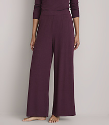 A person stands in wide-leg burgundy pajamas against a plain gray background. carousel Product Image 2
