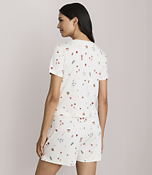 A woman in a cream-colored pajama set with a festive pattern stands against a plain, light-colored background. carousel Product Image 3