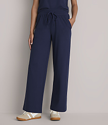 A person stands in navy blue wide-leg pants and sneakers against a plain gray background. carousel Product Image 2