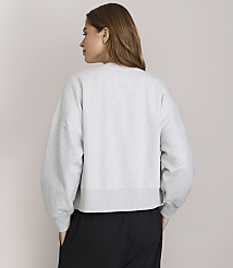 A woman in a grey sweatshirt and black pants stands against a plain white background. carousel Product Image 3