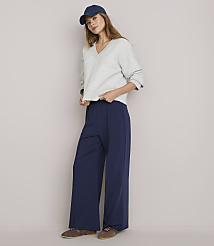 A young woman in a light gray sweatshirt, navy blue wide-leg pants, and a blue baseball cap stands against a plain white background. carousel Product Image 2