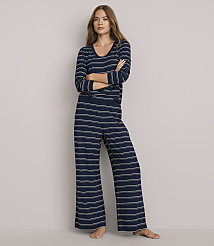 A woman in striped pajamas stands with her arms crossed against a plain white background.