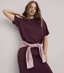 A woman in a burgundy dress with a pink sweater tied around her waist poses against a plain white background. carousel Product Image 1
