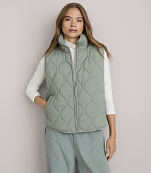 A woman in a light green quilted vest and white turtleneck stands against a plain white background. carousel Product Image 1