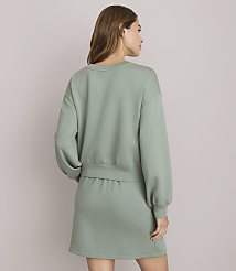 A woman in a sage green sweatshirt and skirt stands against a plain white background. carousel Product Image 3