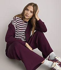 A woman in a striped shirt and burgundy loungewear sits on a plain white background. carousel Product Image 2