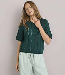 A woman in a green sweater and light blue pants poses against a white background. carousel Product Image 1