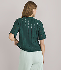 A woman in a green, short-sleeved, open-knit sweater and light green pants stands against a plain white background. carousel Product Image 3