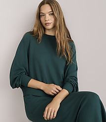 A woman in a teal sweatshirt and skirt stands against a plain white background. carousel Product Image 2