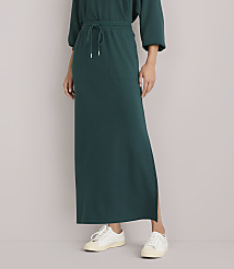 A person wearing a long, dark green dress with white sneakers stands against a plain white background. carousel Product Image 2