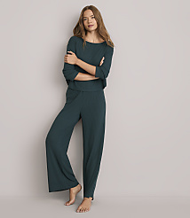 A woman in a teal ribbed pajama set stands with her arms crossed against a plain gray background. carousel Product Image 1