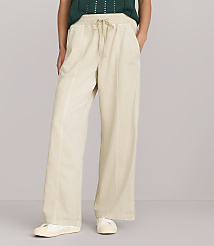 A person stands in the foreground wearing wide-leg cream-colored pants and a green sweater, against a plain white background. carousel Product Image 2